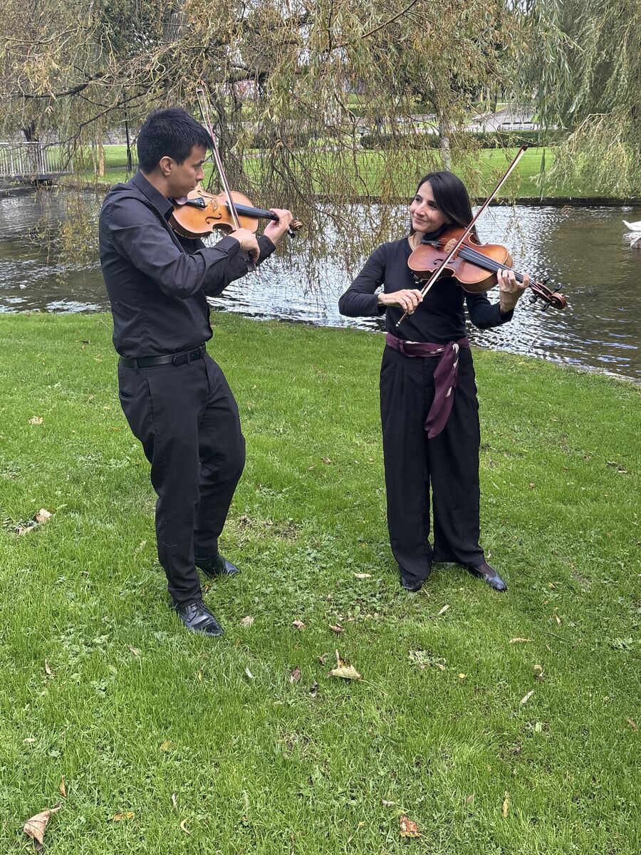 Dúo de violín y viola tocando al aire libre junto a un lago